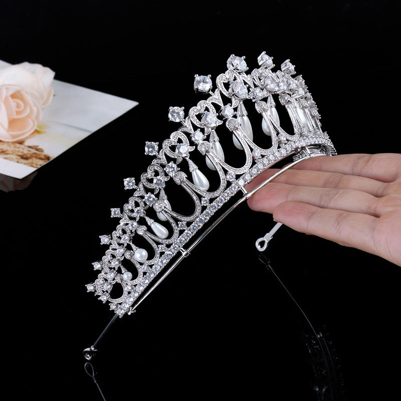 Silver tiara held by a hand with a blurred background