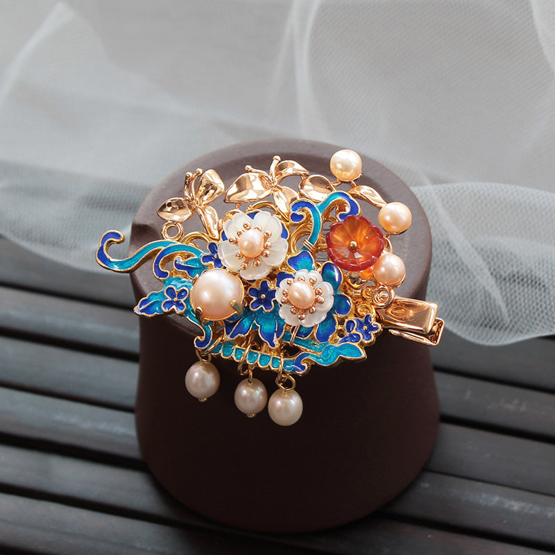 Decorative hair clip with floral design and pearls on a textured surface