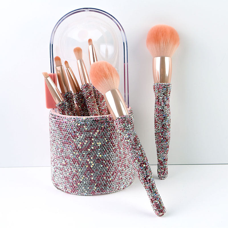 Makeup brushes with glittery handles in a sparkly holder on a white background