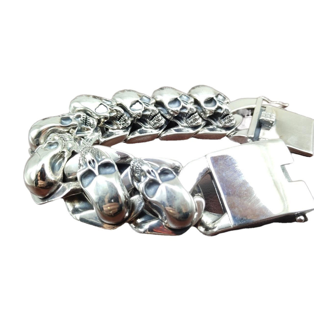 Silver bracelet with skull designs on a white background