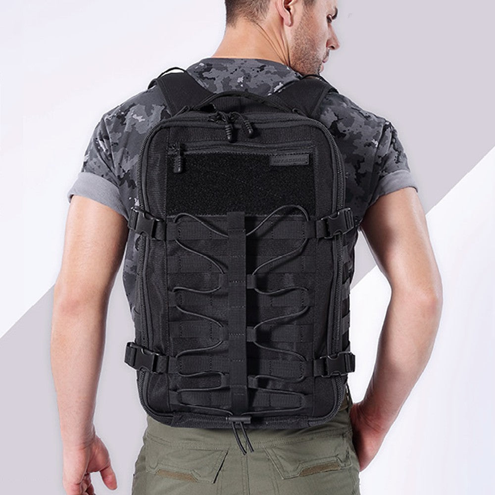 Person wearing a black tactical backpack with camouflage shirt and green pants on a light gray background