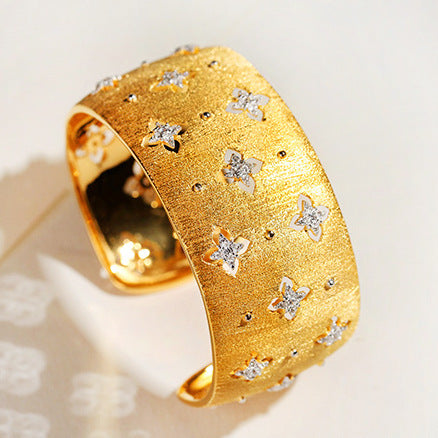 Gold bracelet with star-shaped diamond embellishments on a light background