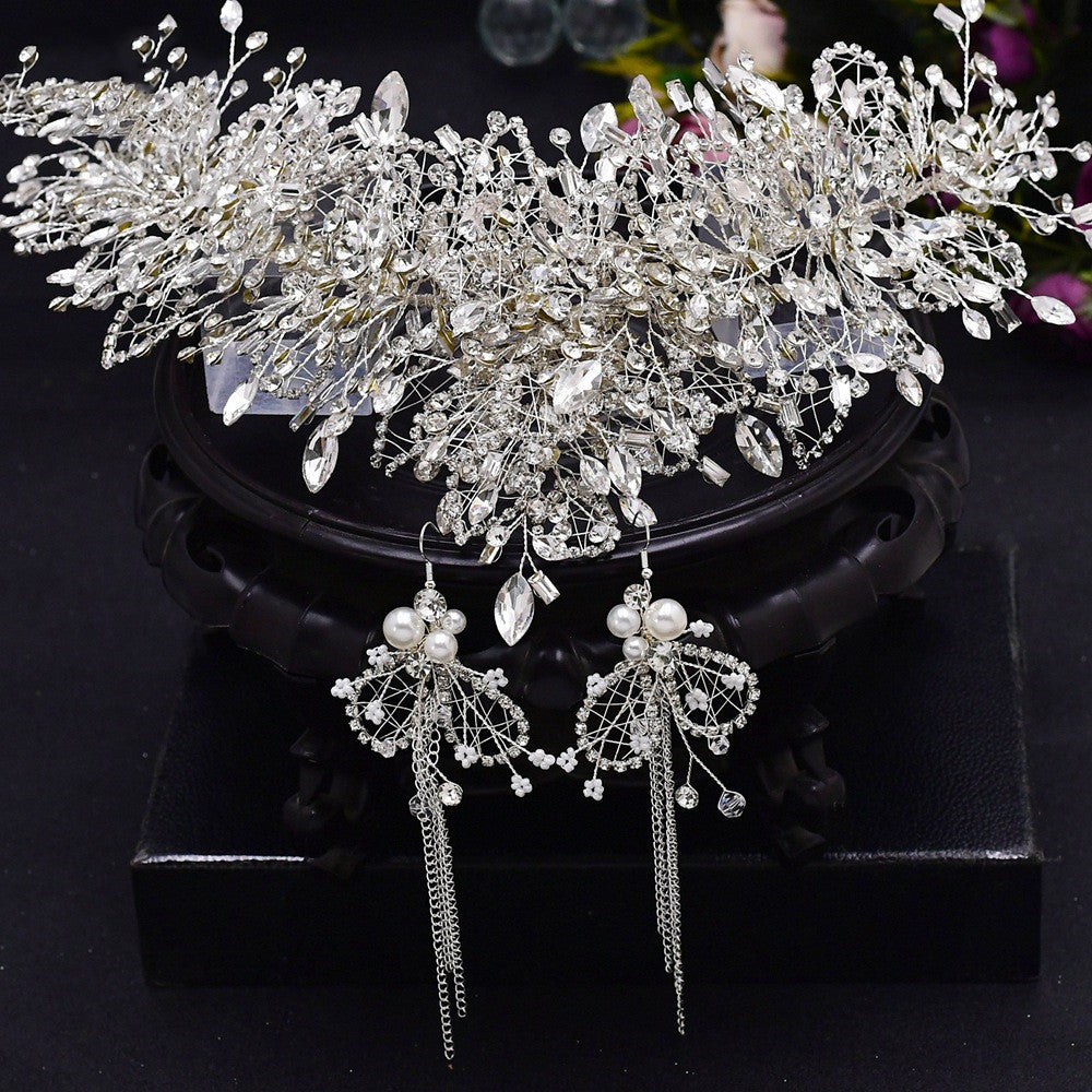 Silver hairpiece with crystal and pearl details on a black stand.