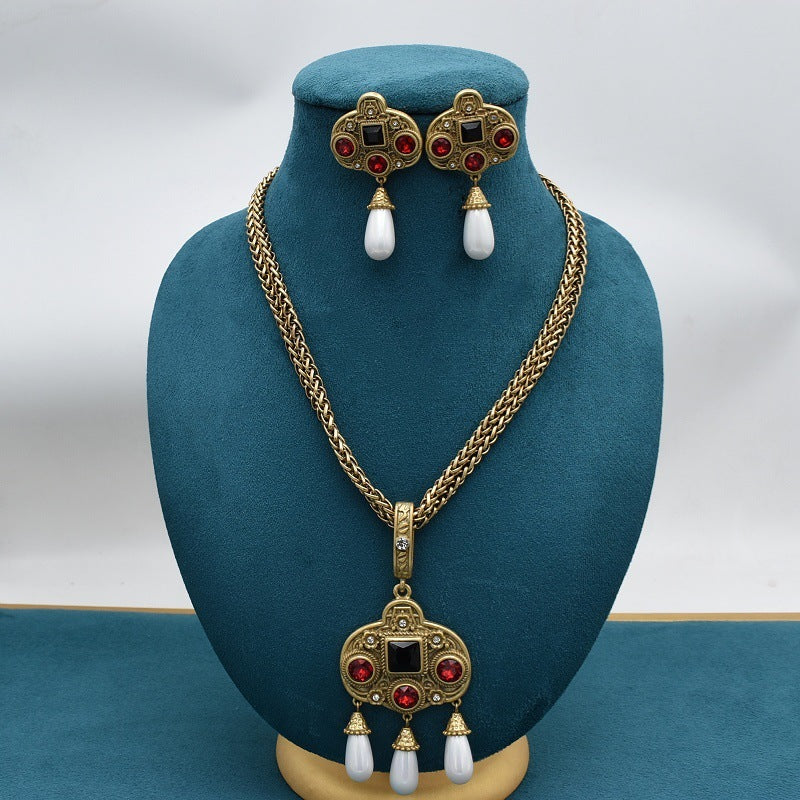 Gold necklace and earrings set on a blue mannequin bust with a white background