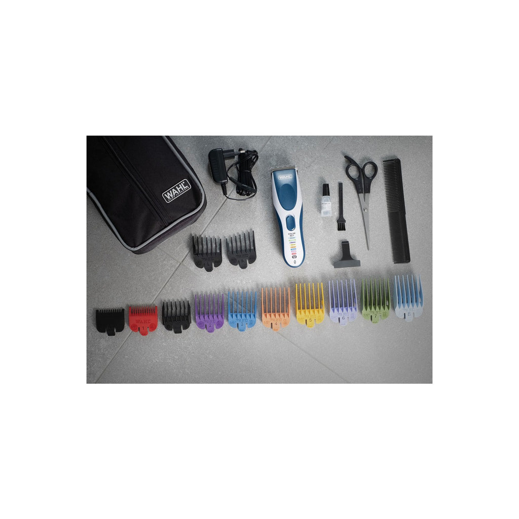 Hair cutting tools including a clipper, scissors, comb, and color-coded guides on a gray surface.