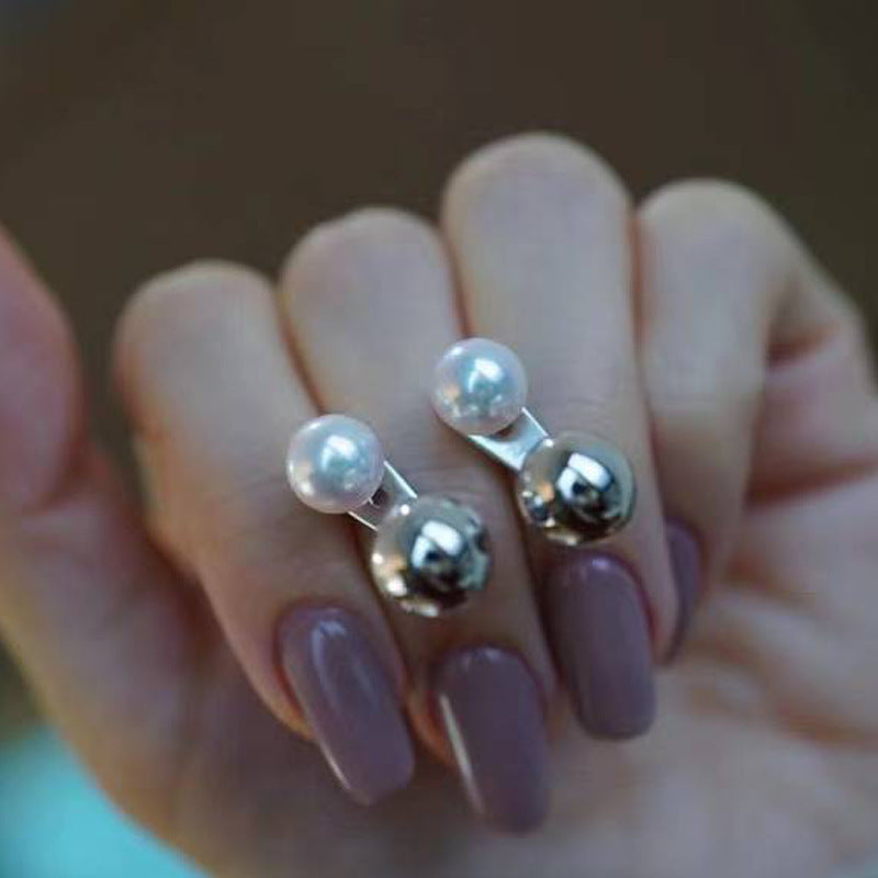 Close-up of a hand wearing a ring with pearl-like beads on a blurred background