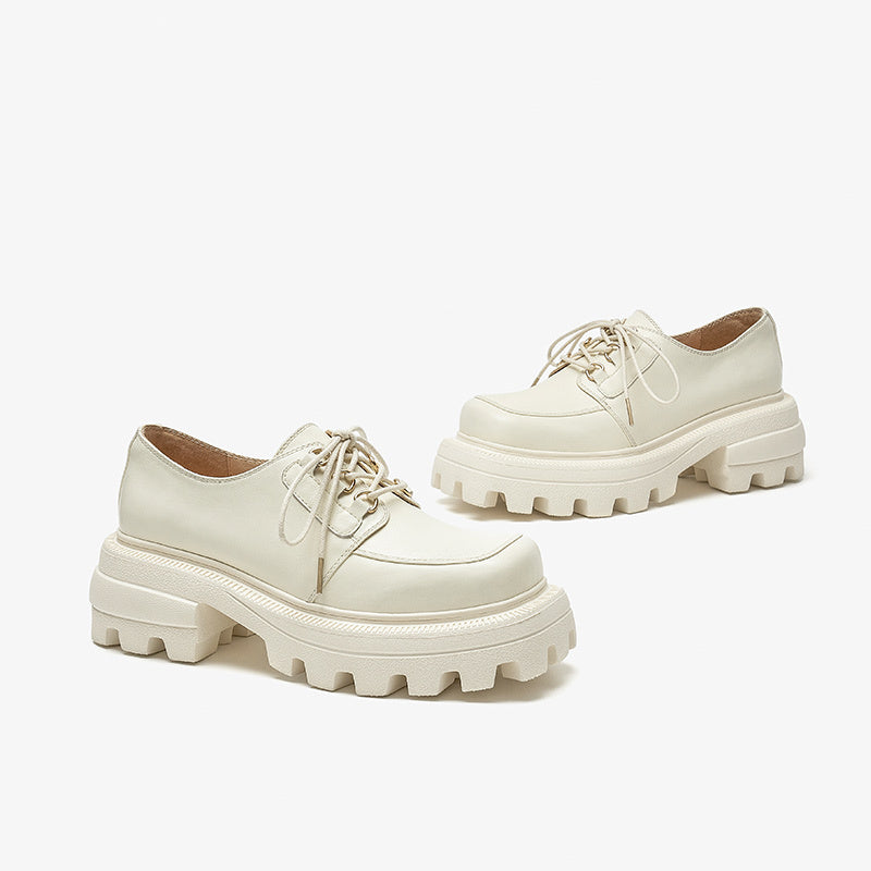 Pair of white platform shoes on a light beige background