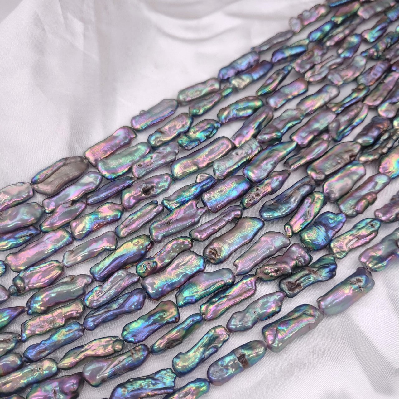 Iridescent shell beads on a white fabric background