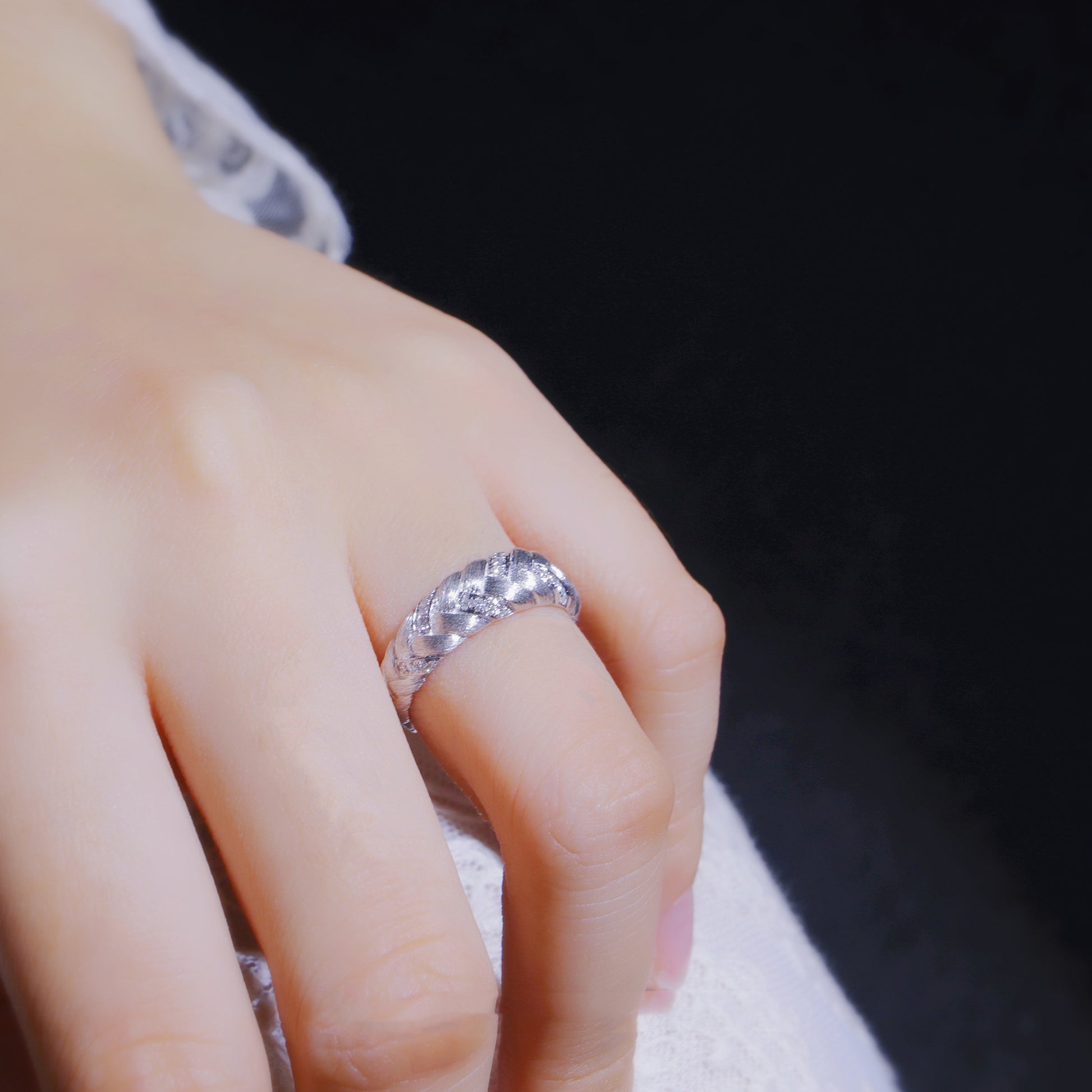 Close-up of a hand wearing a silver ring with a dark background