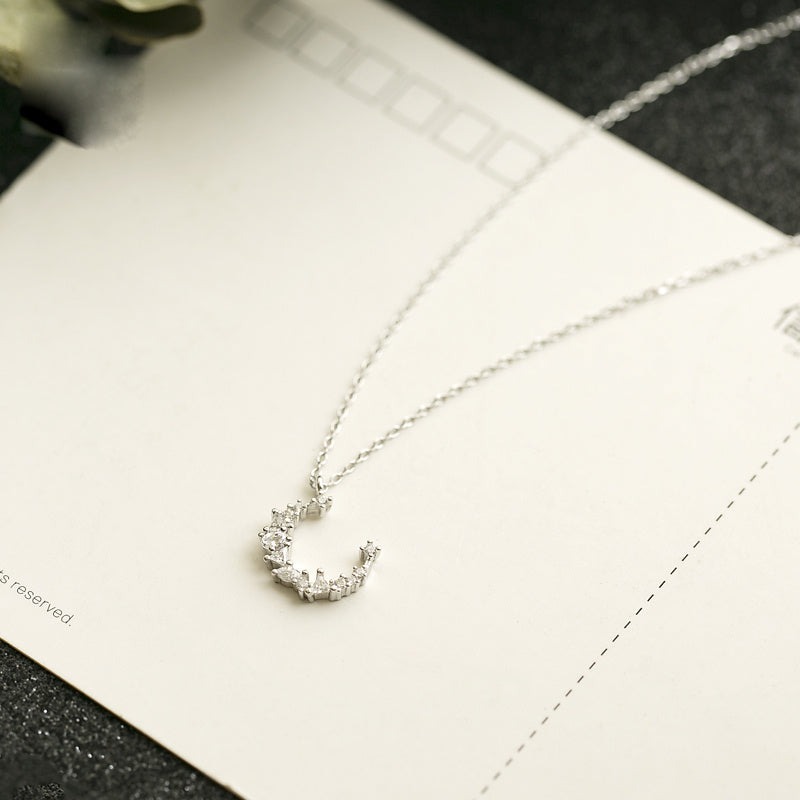 Silver necklace with a heart-shaped pendant on a white surface