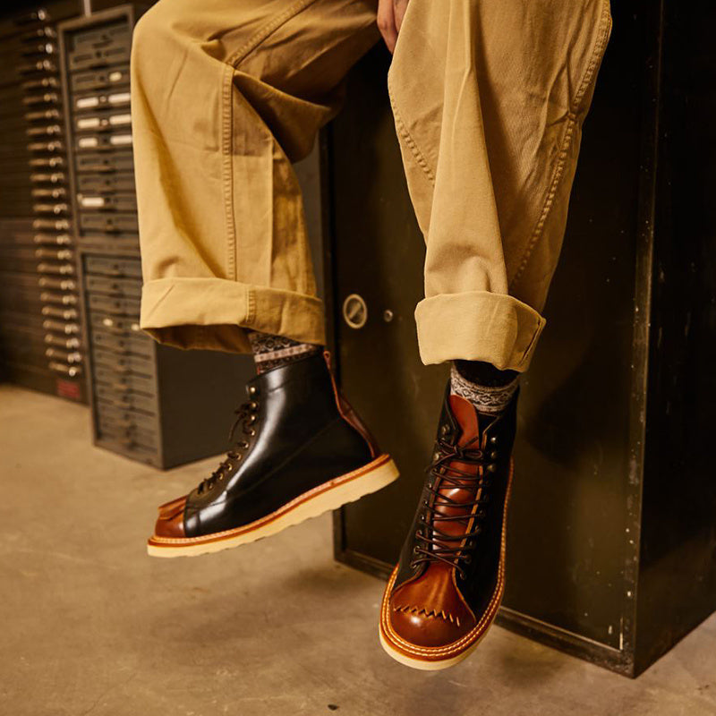Person wearing brown leather boots with a dark background