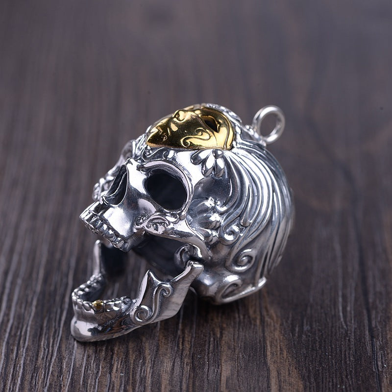 Silver skull pendant with gold interior on a wooden surface