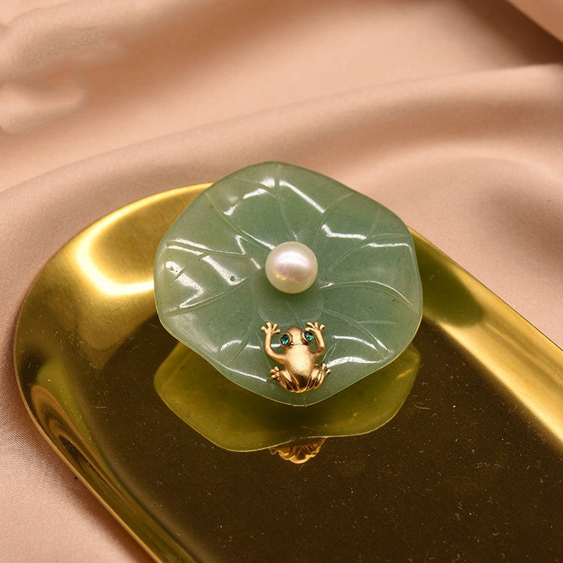 Jade brooch with a pearl and gold frog on a gold and beige background
