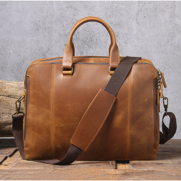 Brown leather bag with a strap on a wooden surface and gray background