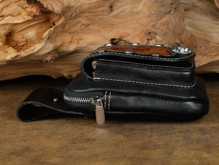 Black leather wallet with decorative elements on a wooden surface