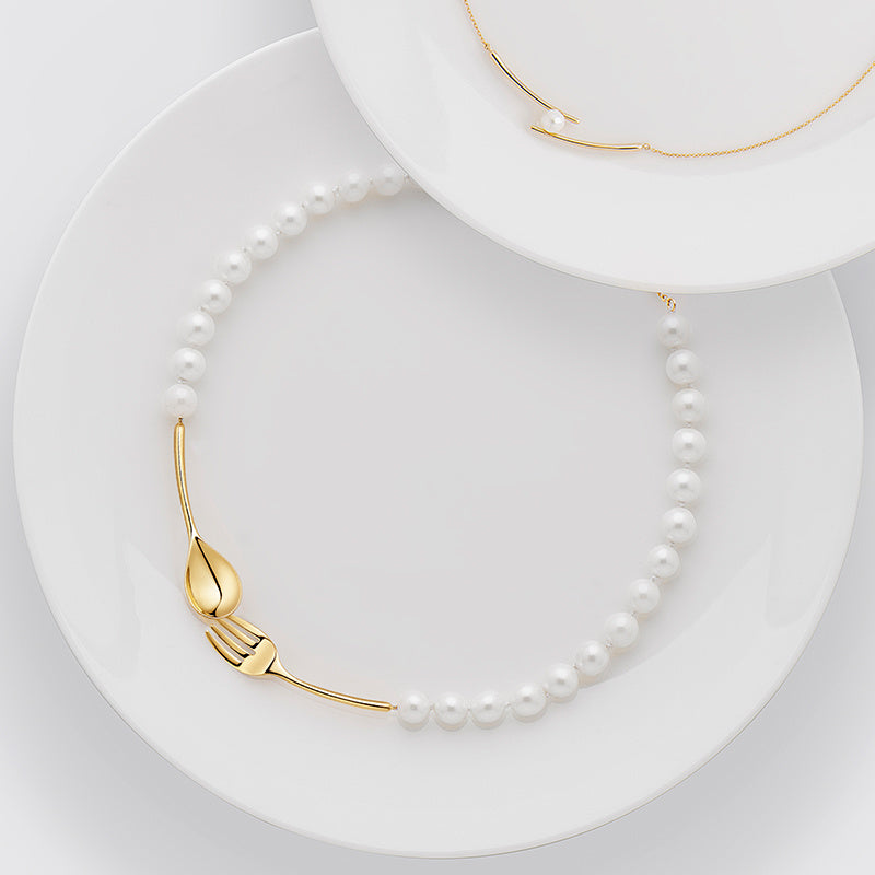 Pearl necklace with gold clasp on a white plate