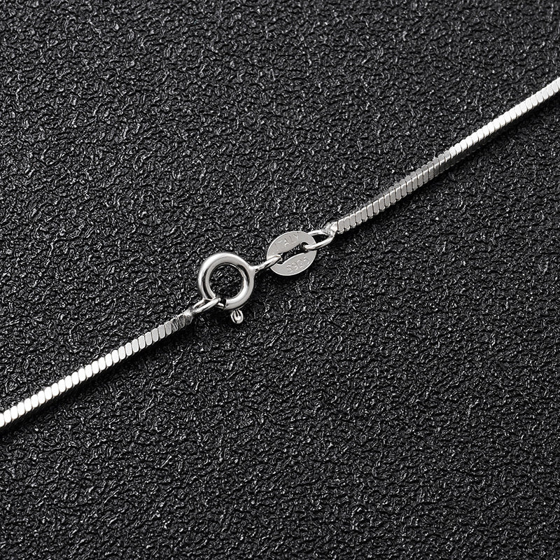 Silver chain necklace with a clasp on a black textured background