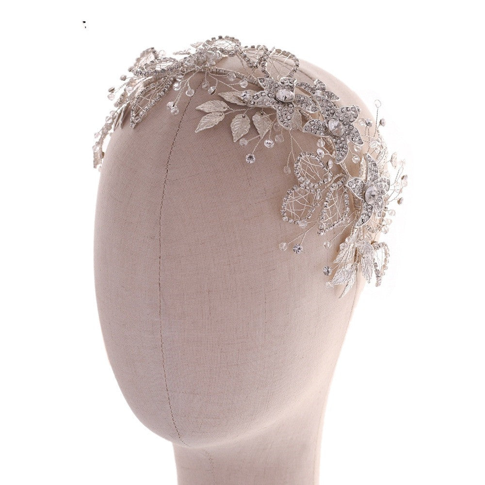 Decorative headband with floral and leaf patterns on a mannequin head against a white background