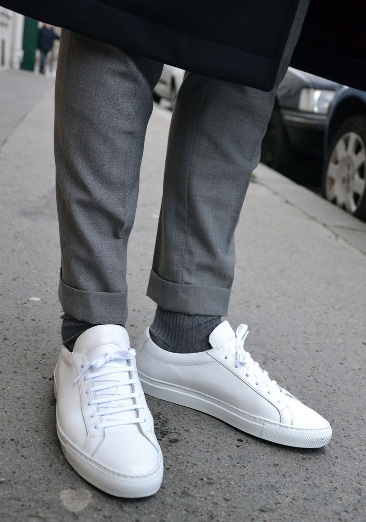 White sneakers worn with gray pants on a street.