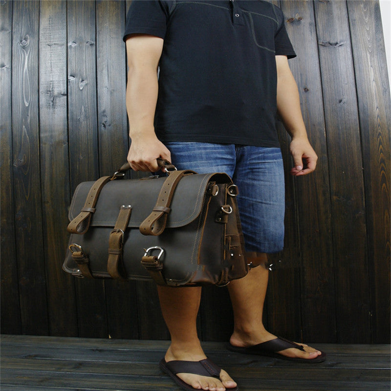 Person holding a leather satchel against a wooden background