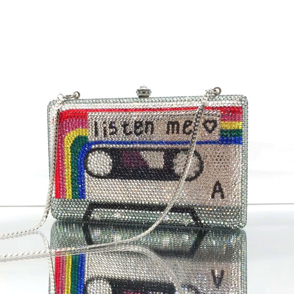 Crystal-embellished clutch shaped like a cassette tape with 'Listen me' text on a white background