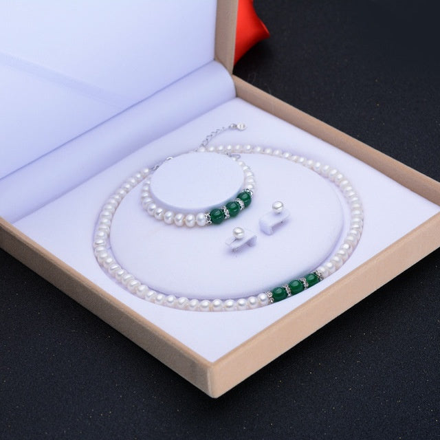 Jewelry set with pearls and green beads in a box on a black background