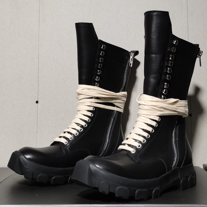 Black leather boots with white laces on a gray background
