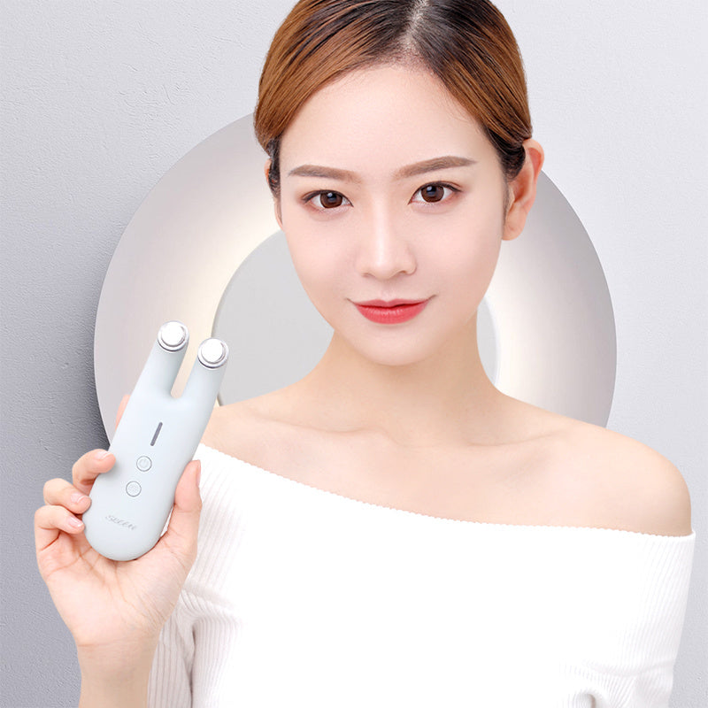 Woman holding a white electronic device against a gray background