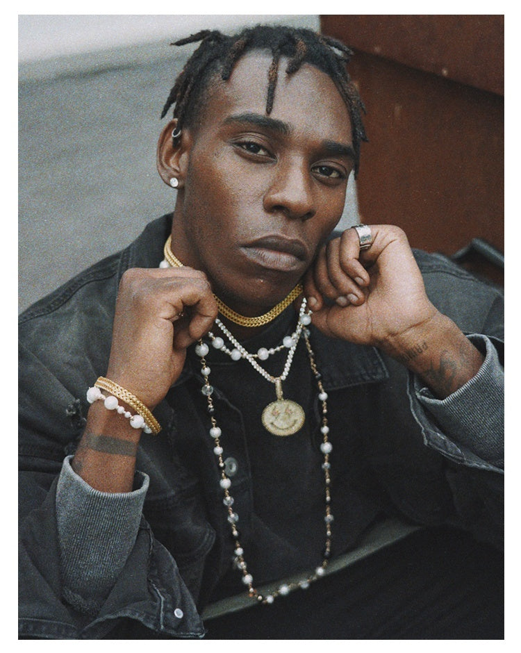 Person wearing multiple necklaces and jewelry with a neutral background
