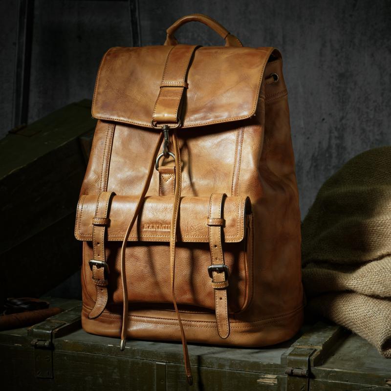 Brown leather backpack on a wooden surface with a dark background