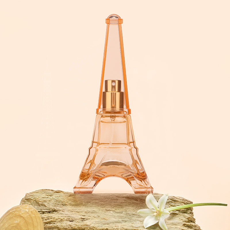 Perfume bottle shaped like the Eiffel Tower on a beige background