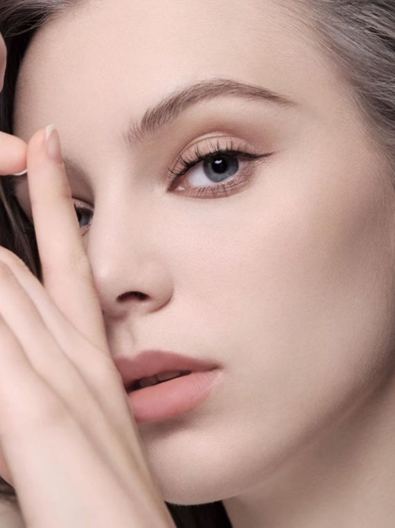 Close-up of a woman's face with soft makeup and a neutral background