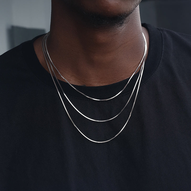 Person wearing a silver necklace against a dark background