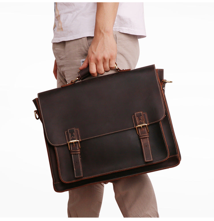 Person holding a brown leather briefcase against a white background