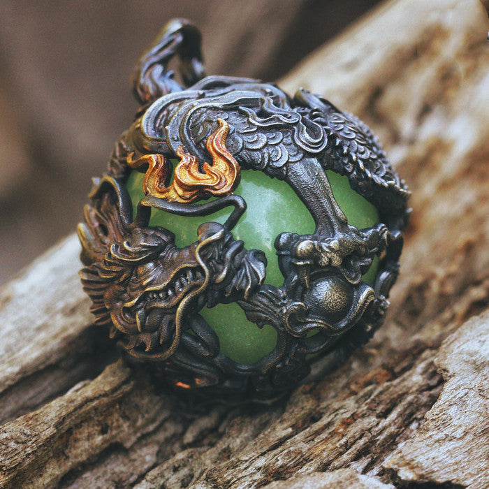 Decorative pendant with green gem and dragon design on a wooden surface