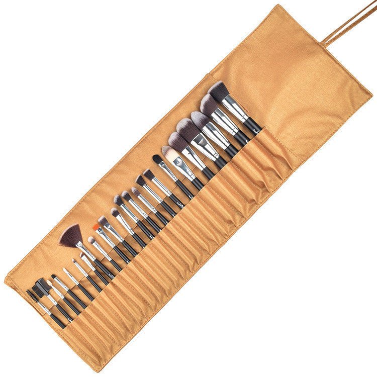Set of makeup brushes in a brown leather holder on a white background