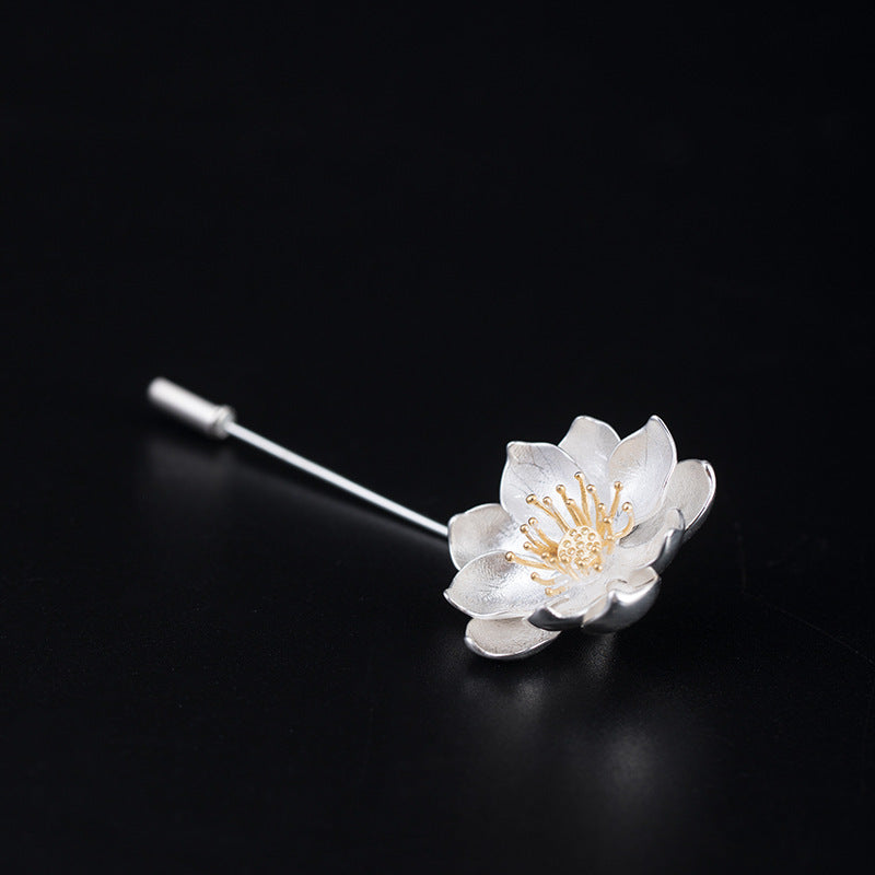 Silver and gold flower-shaped brooch on a black background
