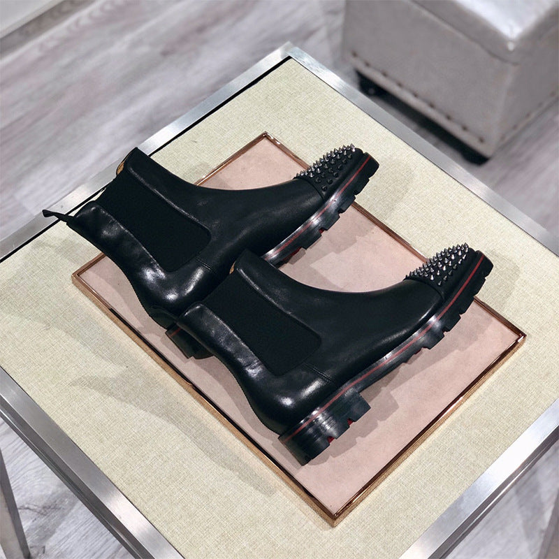 Pair of black leather boots with studded details on a decorative stand.