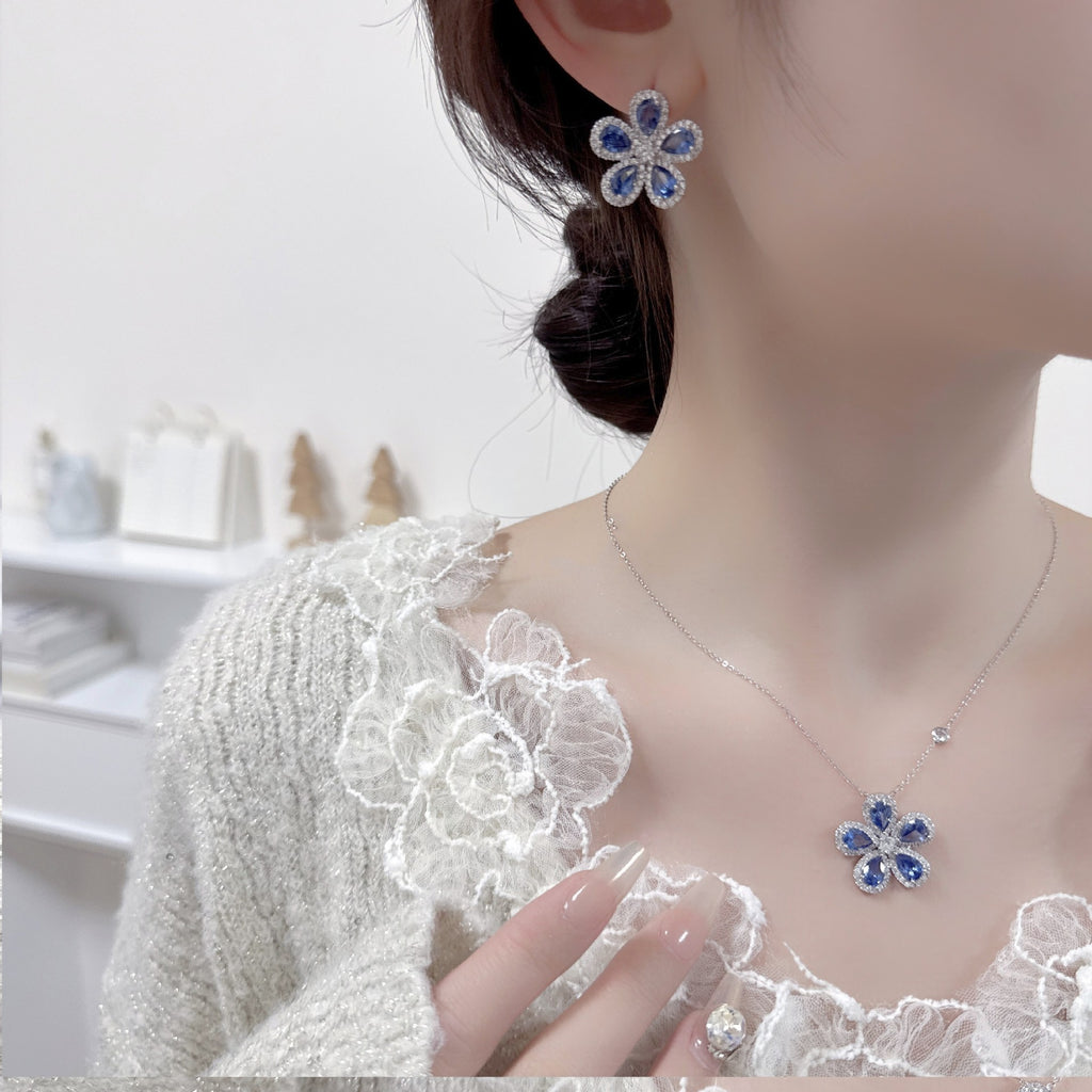 Flower-shaped earrings and necklace worn by a person with a blurred background
