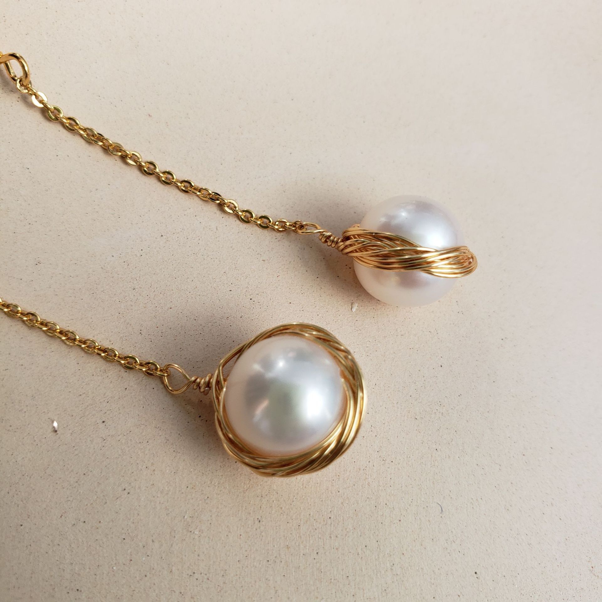 Pearl necklace with gold chain on a beige background