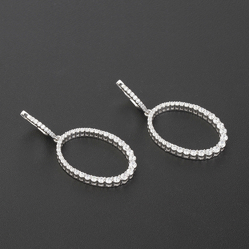 Pair of silver hoop earrings with clear stones on a dark gray background