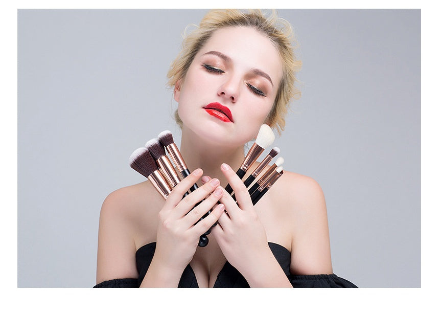 Woman holding makeup brushes against a plain background