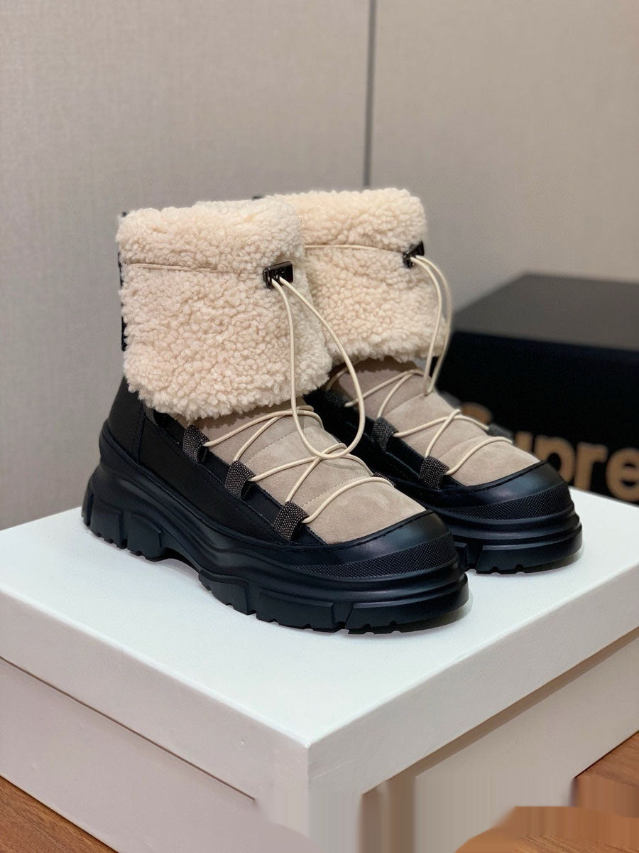 Pair of black and beige winter boots on a white surface with a neutral background