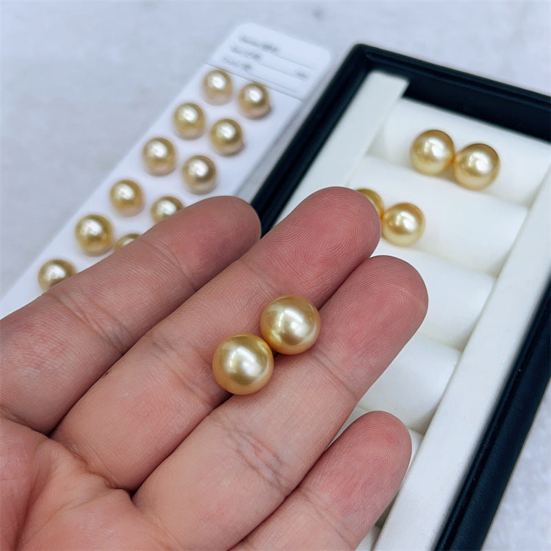 Two pearls held between fingers with a display of pearls in the background