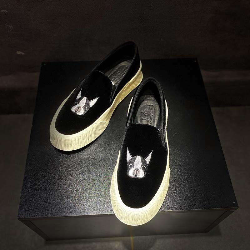 Black loafers with dog face design on a black box