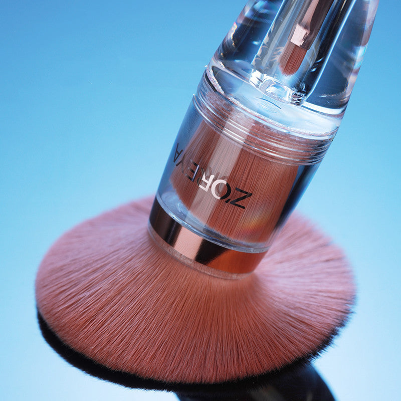 Makeup brush with pink bristles and clear handle on a blue background