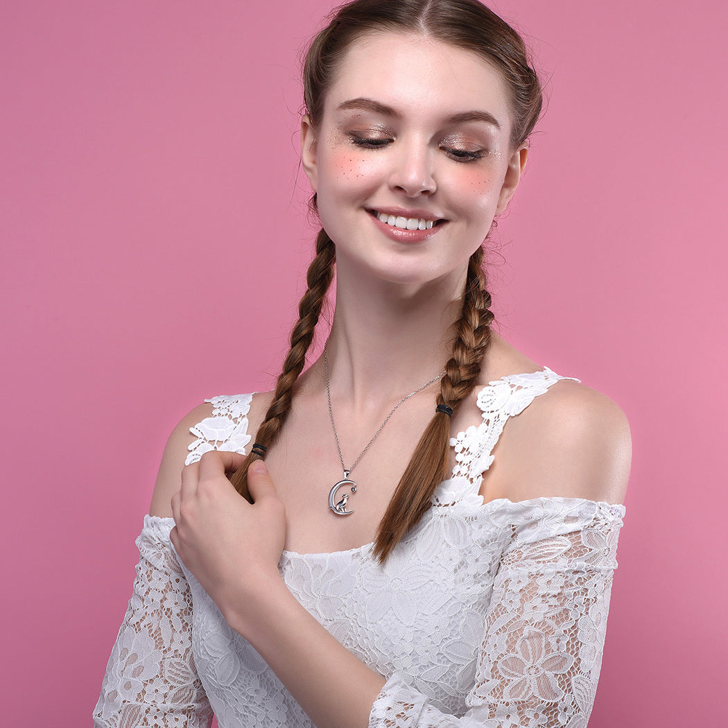 Woman with braided hair wearing a white lace top against a pink background