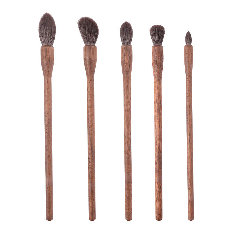 Set of five makeup brushes with wooden handles on a white background