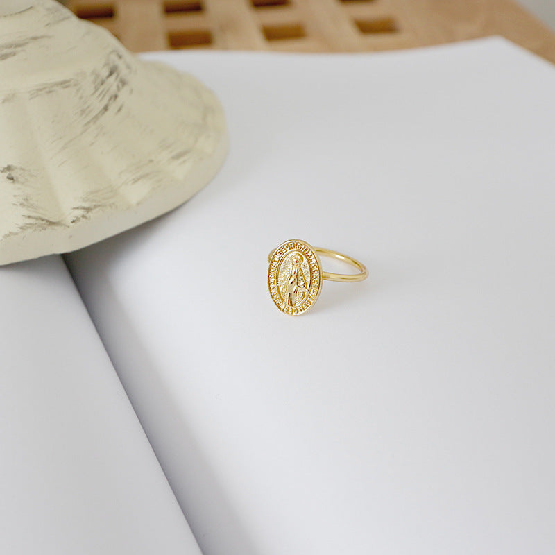 Gold ring with a circular design on a light gray surface