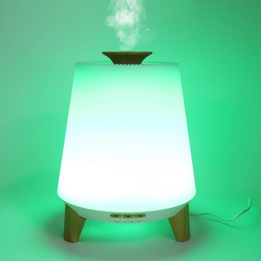 White diffuser with wooden base and legs on a green background